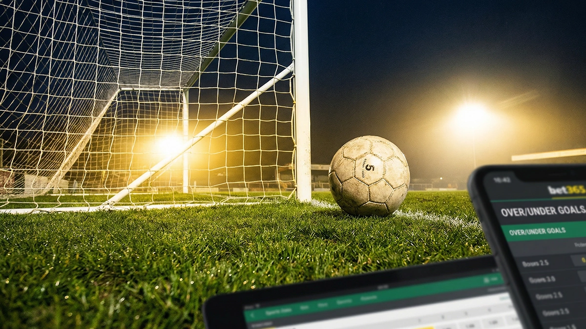 Ballon de football posé devant un but sur un terrain en gazon naturel sous les projecteurs